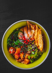 Fresh seafood recipe. Shrimp salmon poke in bowl on black wooden table background