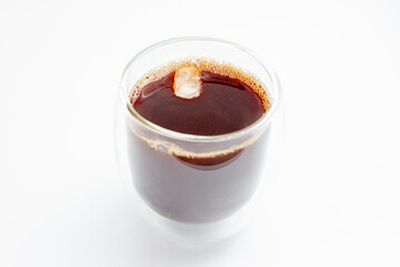 Fresh black coffee in a double glass cup with Ice foam bubbles on a white background