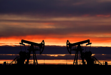 Crude oil pump jack at oilfield on atmospheric sunset backround. Fossil crude output and fuels oil production. Oil drill rig and drilling derrick. Global crude oil Prices, energy, petroleum demand