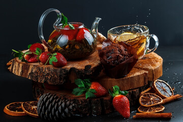 Glass teapot. Still life with hot tea with lemon and strawberries. Wooden stand. Splash.