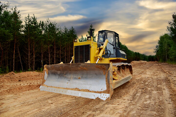 Dozer during clearing forest for construction new road. Bulldozer at forestry work on sunset...