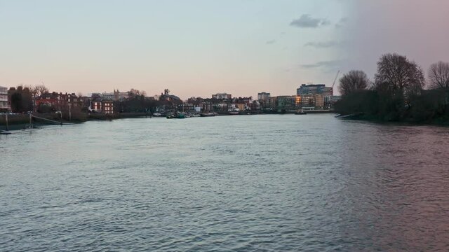 Low drone shot over river thames towards Hammersmith bridge evening