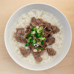 Seolleongtang, Korean Ox Bone Soup, Served with Rice, Noodle, Beef and Scallion in a White Bowl