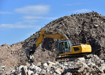 Recycling concrete and construction waste from demolition. Excavator at landfill of the disposa....