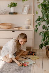 Portrait of a young woman painting at home