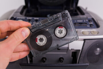 man inserts cassette into tape recorder on white background