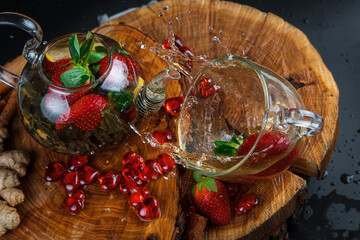 Fototapeta na wymiar Fruit red tea with berries in glass teapot on black background