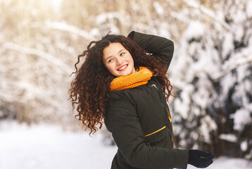 Beautiful happy girl with long hair in a winter park on a sunny day