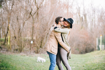 Young caucasian happy couple in love hugging and cuddling in a park kissing