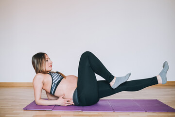 Fototapeta na wymiar Young beautiful caucasian pregnant woman training at home