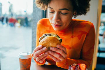 Young beautiful multiethnic woman eating a delicious burger