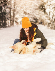 Fototapeta na wymiar Young happy girl has fun playing with her dog th winter outdoors