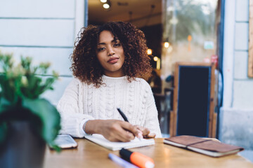 Thoughtful black woman writing notes in notebook