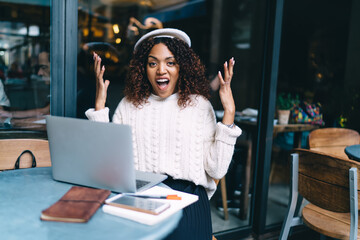 Portrait of dark skinned curly woman blogger influencer irritated with software problems while share multimedia content online, angry african american emotional female student having trouble with 4G