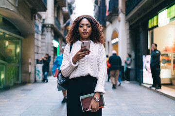 Young female browsing smartphone on city street