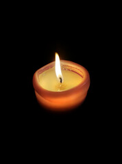 Single lit candle with quite flame on black background. Candle burning at night. Vertical shot.