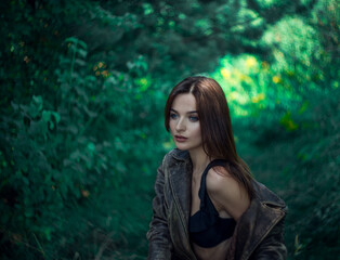 Beautiful brunette girl with blue eyes in the forest. Witching look. Sun spots and glare. Effective bokeh. Selective focus. Blurred background.