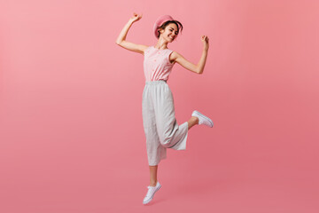 Carefree white girl funny dancing with hands up. Studio shot of blissful laughing woman in french...
