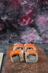 Maki rolls with red caviar topping on a wooden platter