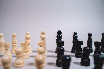 white and black chess pieces stand opposite each other on a gray background