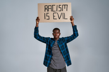 Serious young african american man in casual clothes looking at camera, holding demonstration...