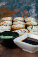 Hot sushi rolls on a wooden board with soy sauce and wasabi