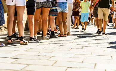 Many people walk in the city center in the pedestrian zone..People on foot wait in line.