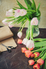 red spring tulips on a blue textured background, next to twine rope and scissors, preparing bouquets for the holiday