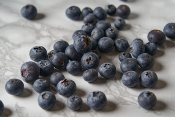 A group of fresh blueberries on a white and black marble table. 