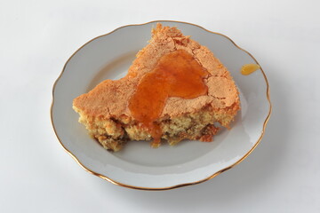 slice of charlotte with apples and maple syrup on a white background