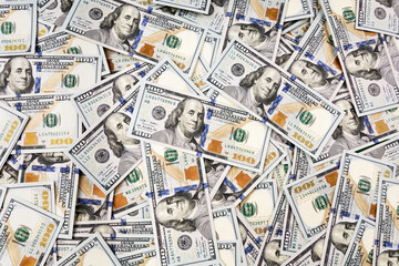 Pile of dollars lies on the table. One hundred dollar bills dumps on table. Background for design from lot of money. View from above
