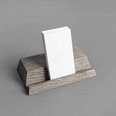 Blank business cards on wooden holder at gray background. Responsive design mockup.