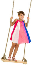 Cute happy girl standing on wooden swing