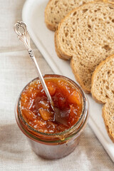 Homemade apple jam marmalade with cloves and cinnamon from organic apples  in glass jar and  wholemeal bread near vintage teaspoon. Homemade autumn jam preserves. Apple jam sandwich  toast breakfast 