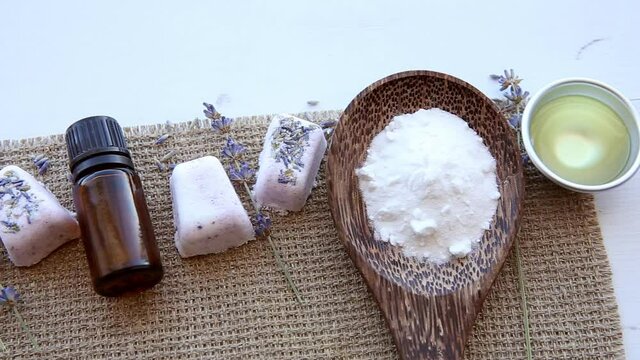Flat lay view of small cube shape bathroom bath fizzies on wood tray, surrounded by ingredients. Making homemade small bath fizzy.