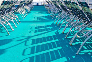 Outdoor pool deck with sun loungers and deck chairs on modern cruiseship or cruise ship liner