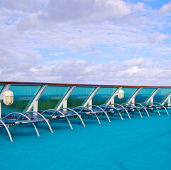 Outdoor pool deck with sun loungers and deck chairs on modern cruiseship or cruise ship liner