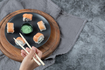 Salmon maki rolls in a white plate with wasabi sauce