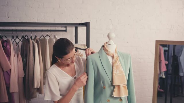 Designer measuring jacket on mannequin in workshop