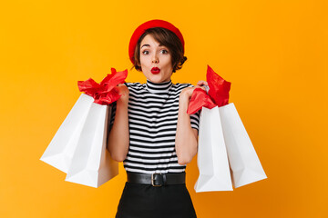 Appealing shopaholic girl standing on yellow background. Studio shot of glamorous lady in striped shirt.