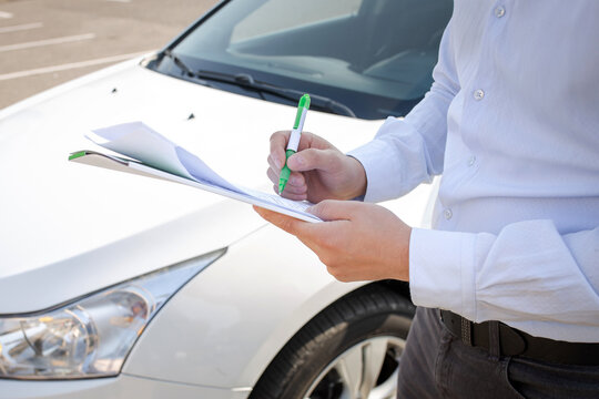 agent fills out documents on the background of the car