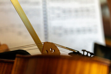 close up of a violin and bow, a sheet of notes (score) in the background, music.