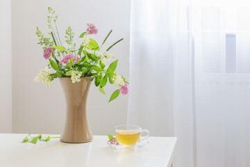 cup of tea and flovers on table at home
