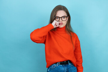 Pretty woman with long hair wearing a casual sweater and glasses over blue background mouth and...