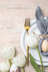 Easter holiday table setting with bunny  from egg on white plate and tulips flowers.  Gray concrete table, top view with copy space for text. Happy Easter background