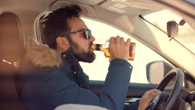 Drunk Driver Sitting On Car.Tired Man Illegal Vehicle Driving.Drunken Drive Risk Car Accident.Man Holding Alcohol Bottle In Car. Dangerous On Road Drunk Driving. Stress Unlawful Intoxicated Drive Auto