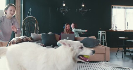 Family together on quarantine. Two kids and white dog run around young smiling mother working from home using laptop. - Powered by Adobe