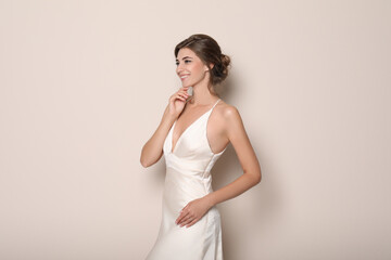 Young bride wearing beautiful wedding dress on beige background