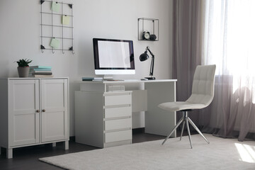 Fototapeta na wymiar Comfortable white chair near desk in stylish office interior