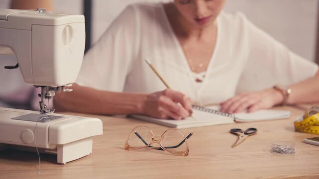 Cropped view of sewing machine, smartphone and needless near designer
